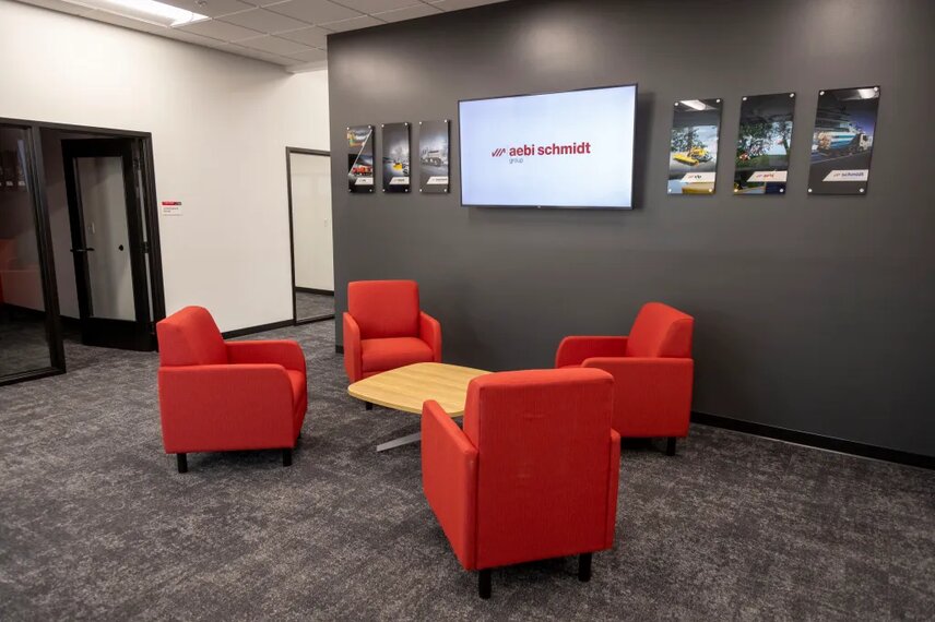 The reception area and lobby of the new facility features color-matched comfortable seating and a large video monitor flanked by product images of the six Aebi Schmidt brands sold in North America.